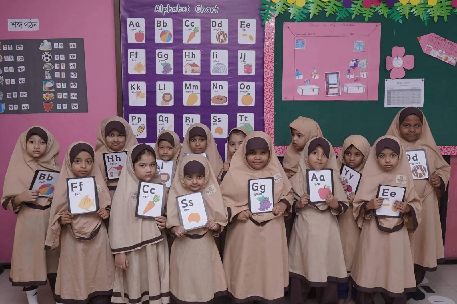 Students displaying alphabet learning cards
