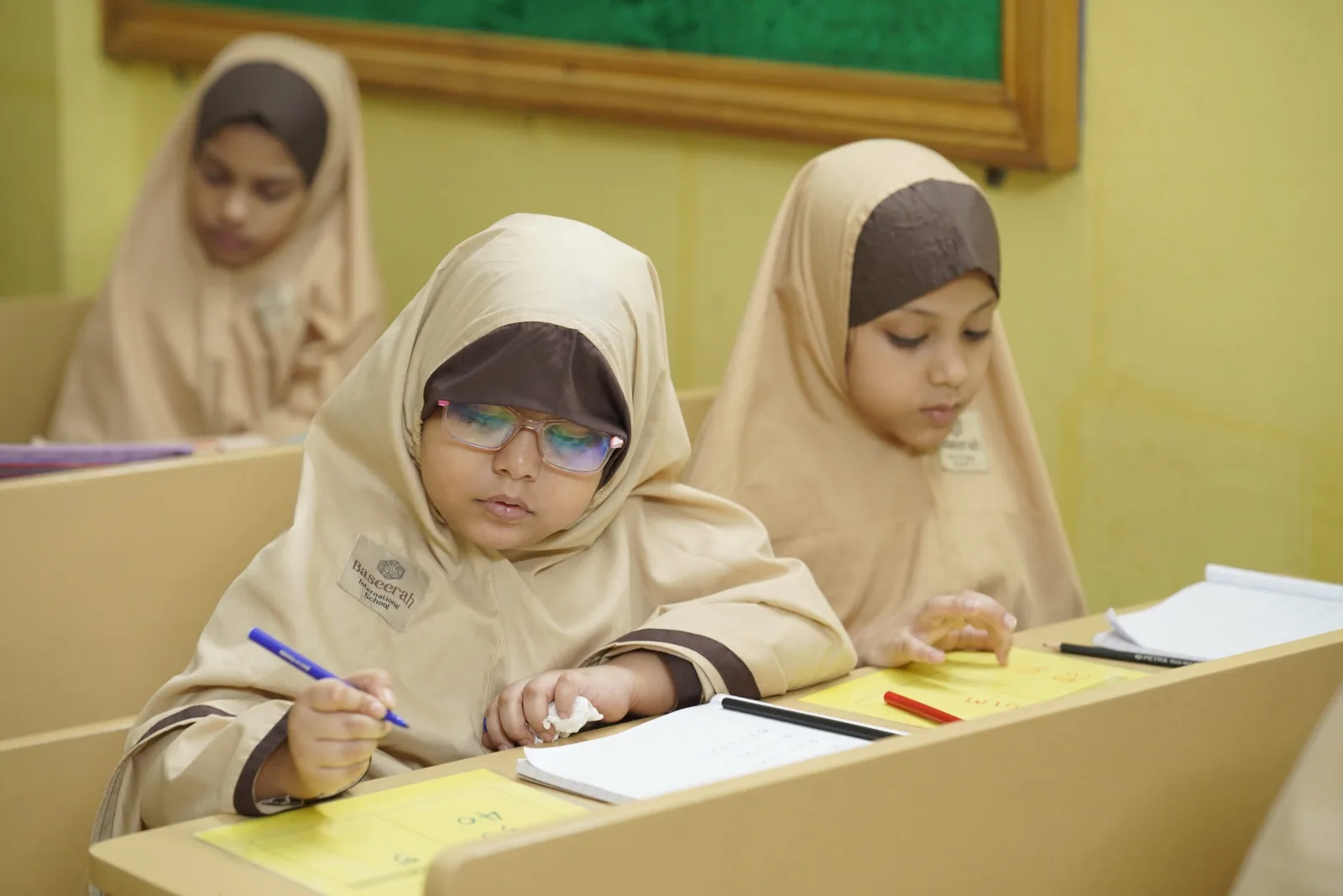 Baseerah girls writing attentively at their desks