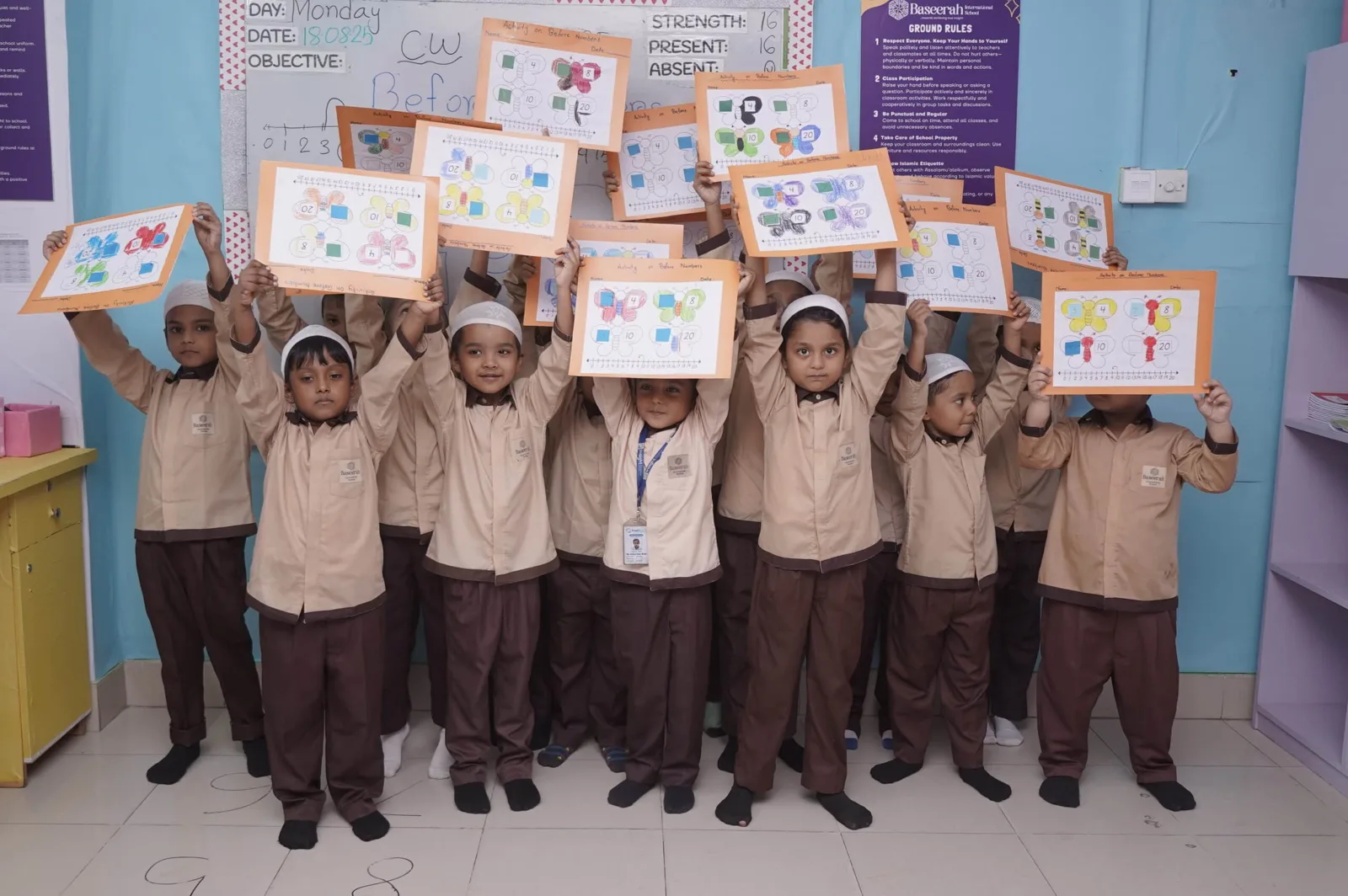 Baseerah children proudly displaying their classroom artwork
